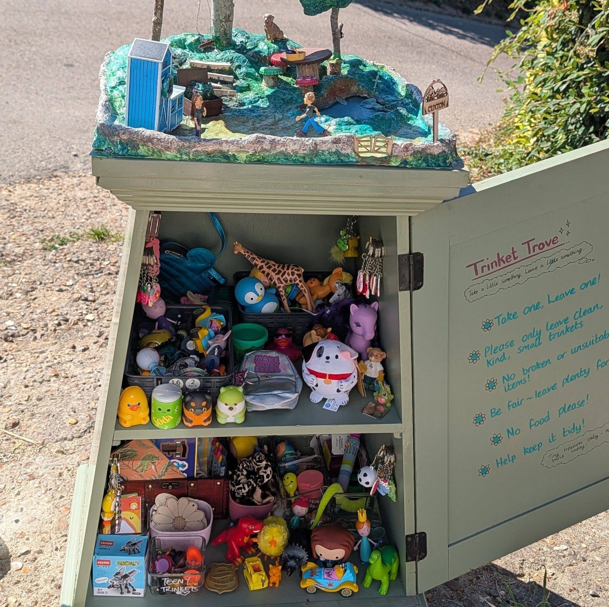 The Trinket Trove cabinet at the end of the drive, its shelves filled with small swapped toys, keyrings and figures